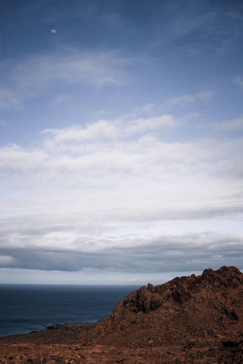 Free A serene view of the Galapagos Islands with a rocky coast, ocean, and moonlit sky. Stock Photo