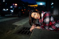 夜间照片，一名穿着格子衬衫的女子躺在街上