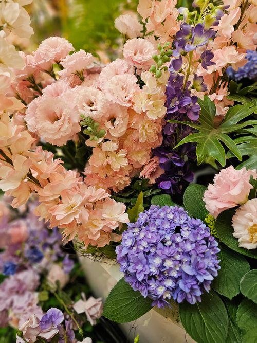 Free A vibrant floral arrangement featuring pink carnations, purple hydrangeas, and lush green leaves. Stock Photo