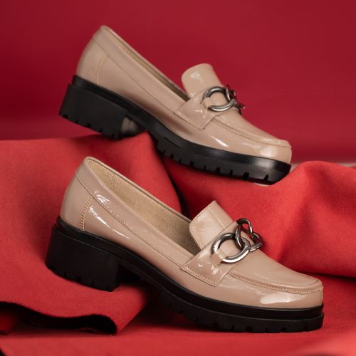 Free Stylish beige loafers with metallic detail showcased elegantly against a bold red backdrop, highlighting contemporary footwear design. Stock Photo