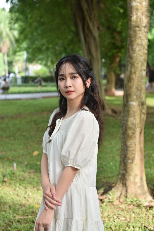 Free Portrait of a young woman standing gracefully in a green park setting. Stock Photo