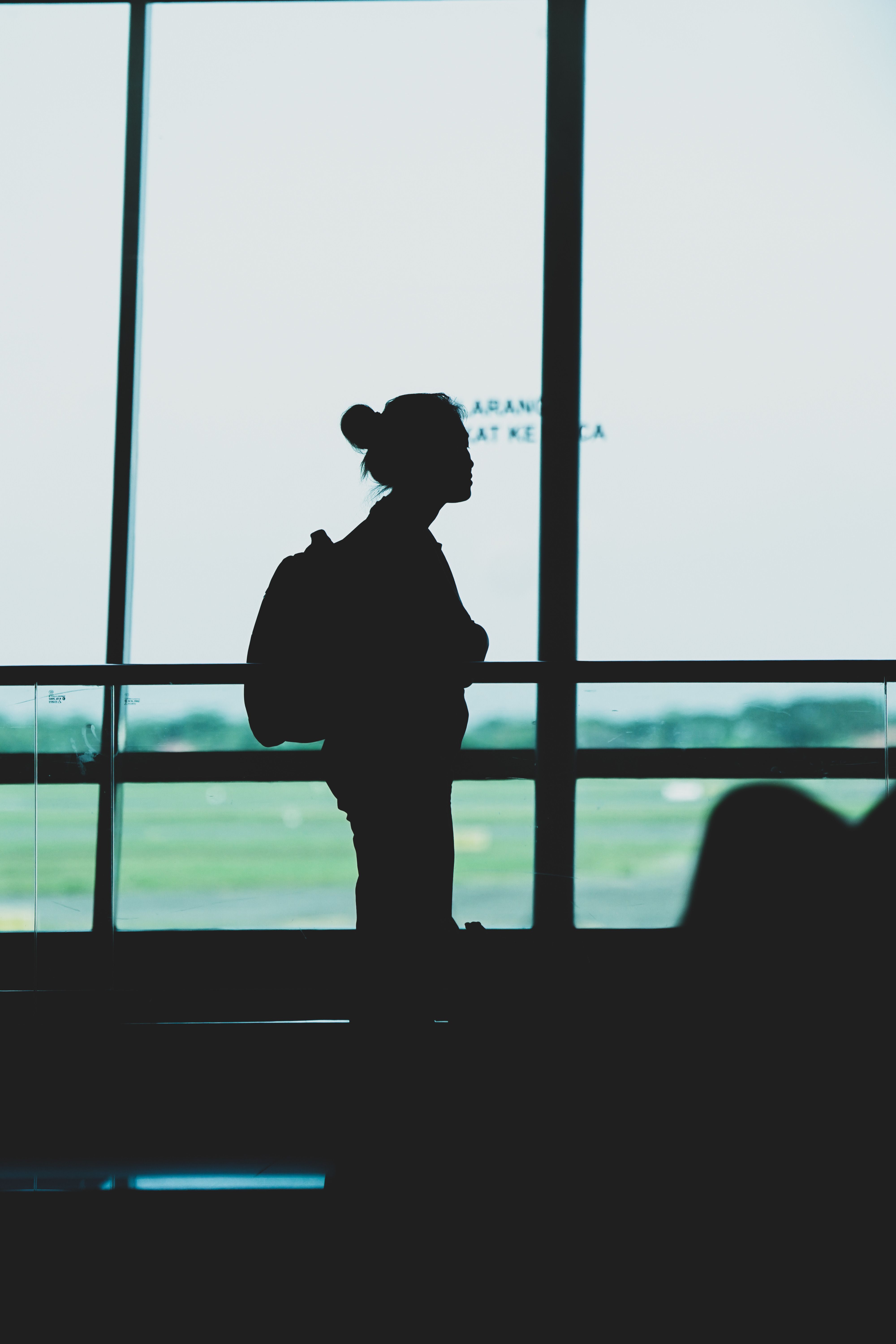 Silhouette of a woman with a backpack standing at Surabaya airport terminal, Indonesia.
