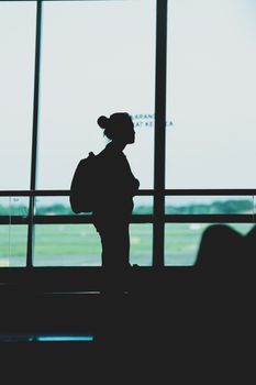 Silhouette of a woman with a backpack standing at Surabaya airport terminal, Indonesia.