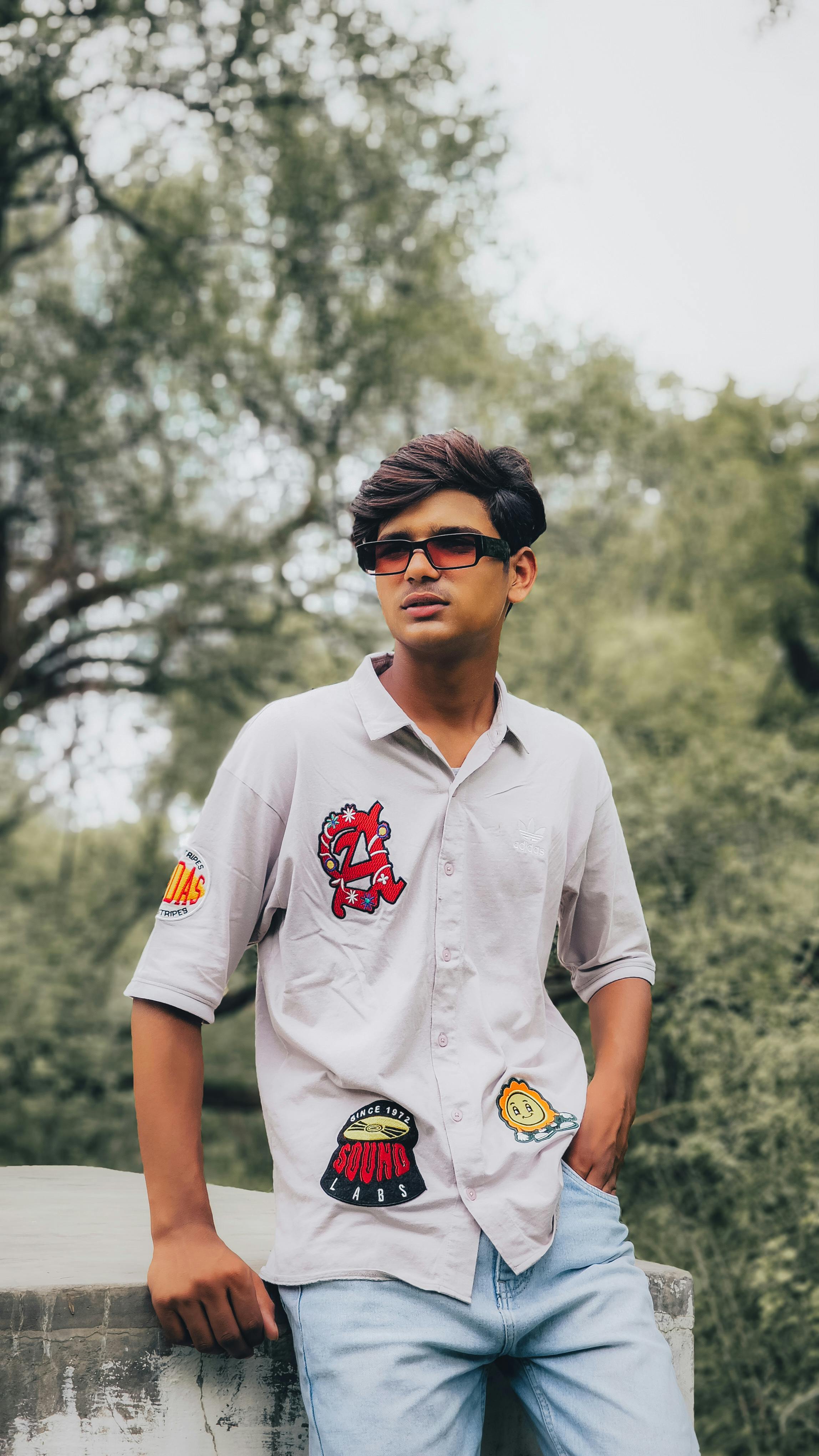 Young man in casual attire and sunglasses enjoying a sunny day at a park.