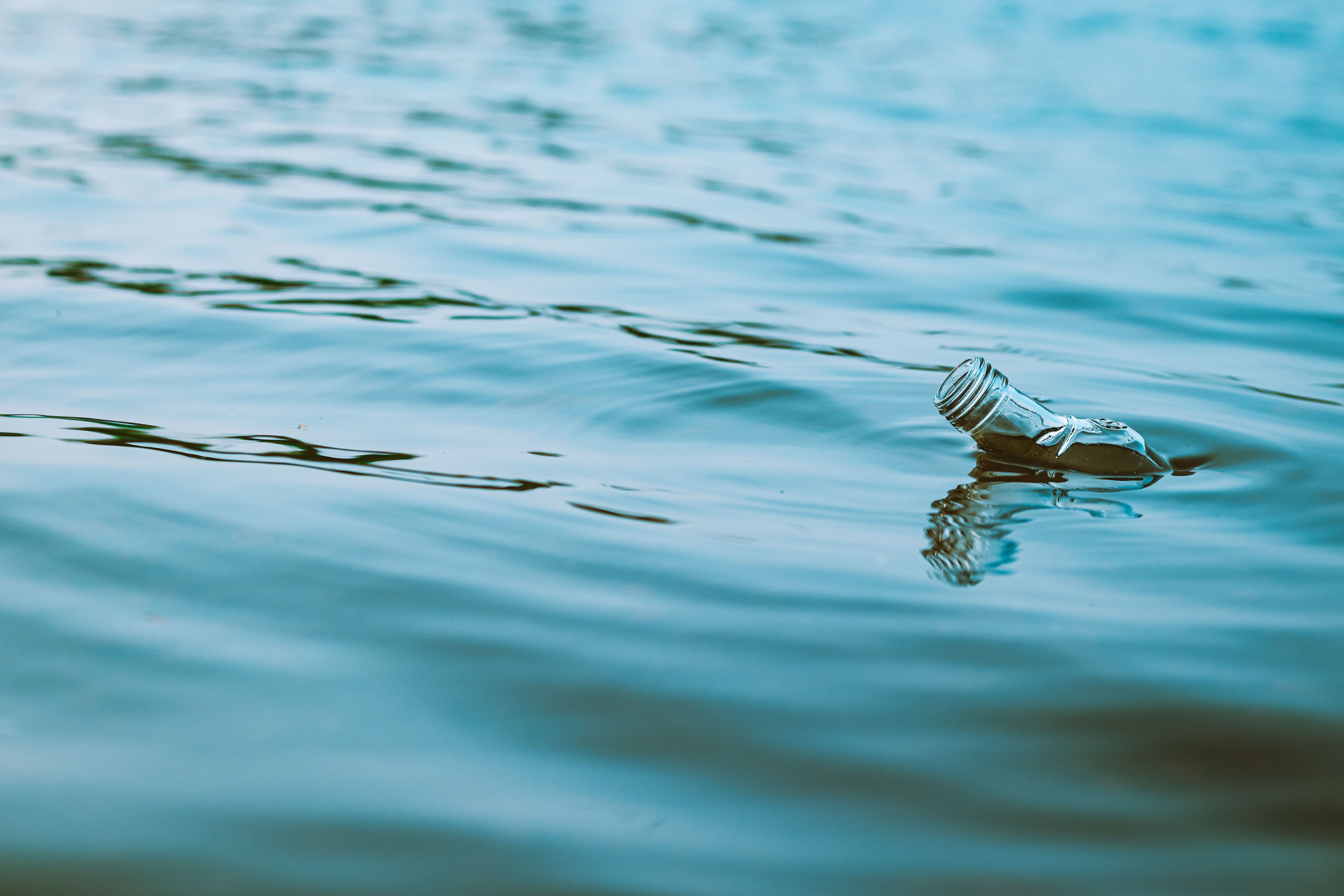 Close-up of a plastic bottle floating on rippling water, highlighting environmental pollution.