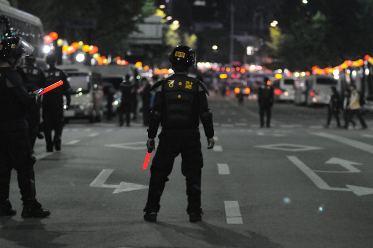 Police Standing On Gray Asphalt During Nighttime