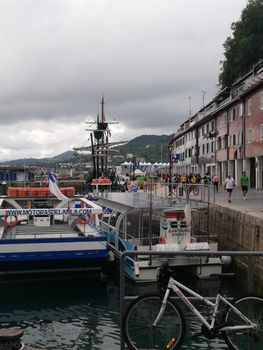 View of the bustling harbor in Donostia-San Sebastian with boats and nearby buildings.