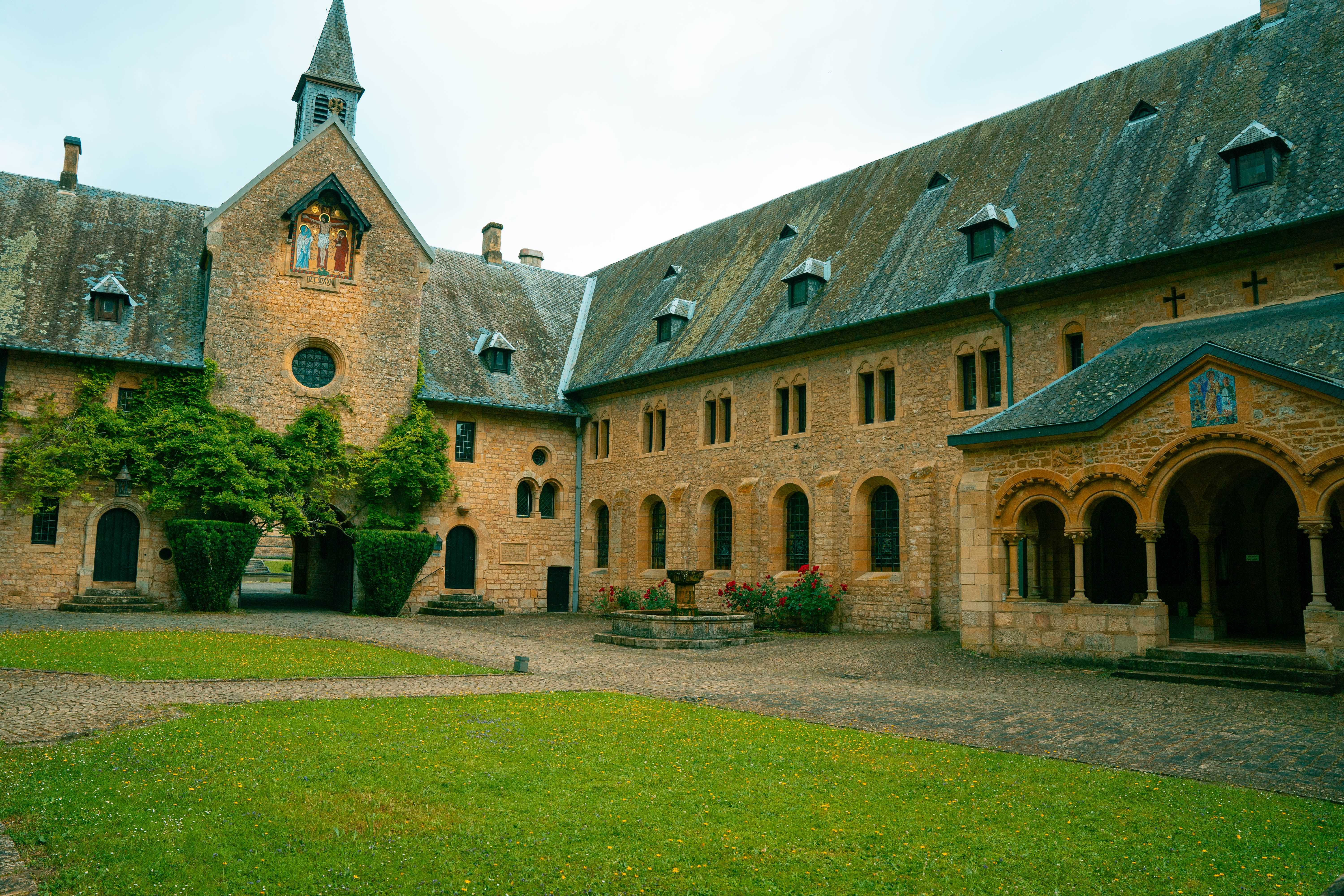 Stone abbey courtyard with medieval architecture and lush greenery.