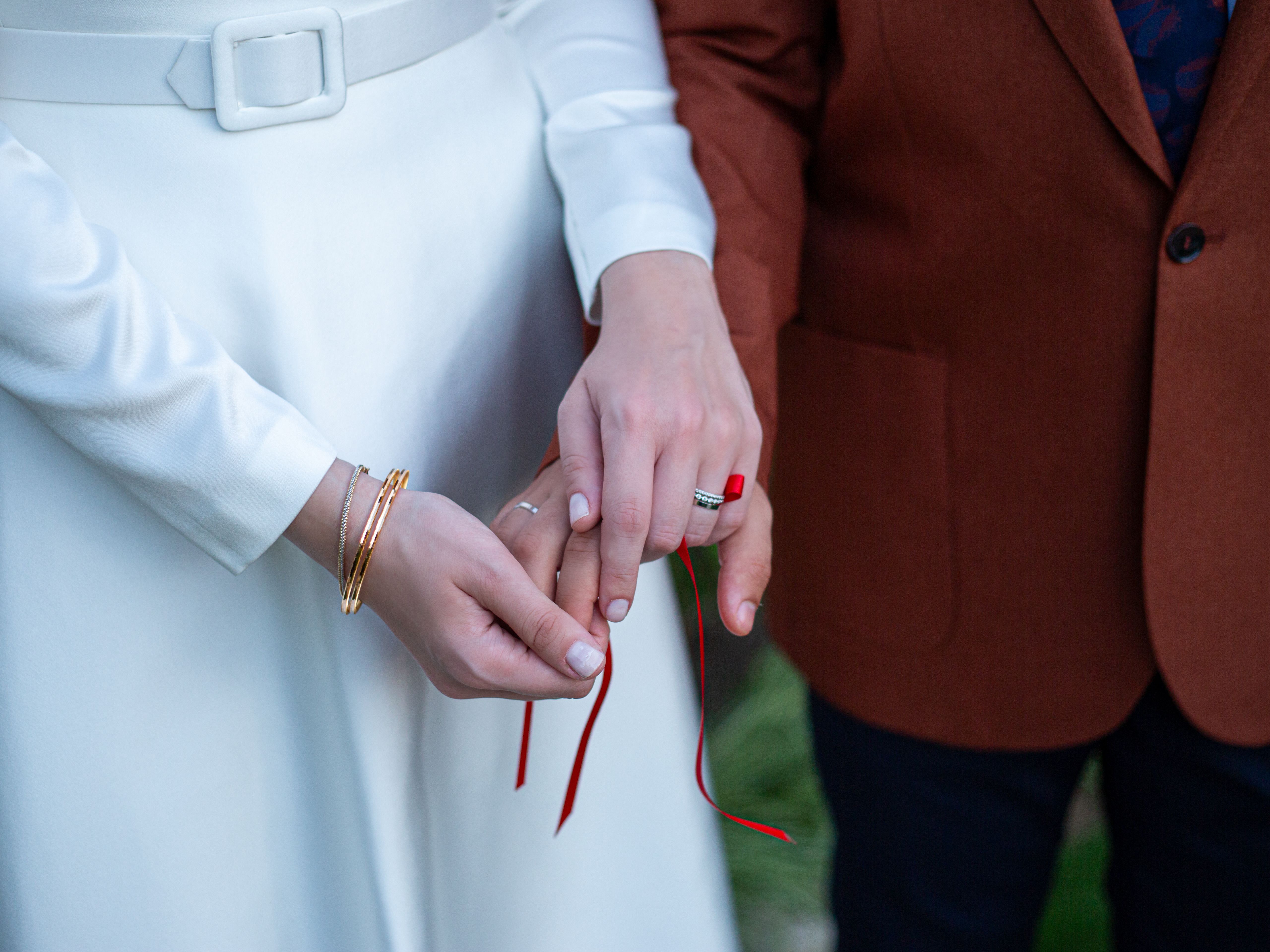 Two hands tied together with fabric ribbon, symbolizing commitment and connection.