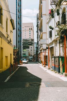 Sunlit urban alleyway in Kuala Lumpur with colorful walls and buildings, showcasing city life.