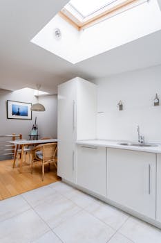 Bright minimalist kitchen interior featuring skylights and sleek white cabinetry.