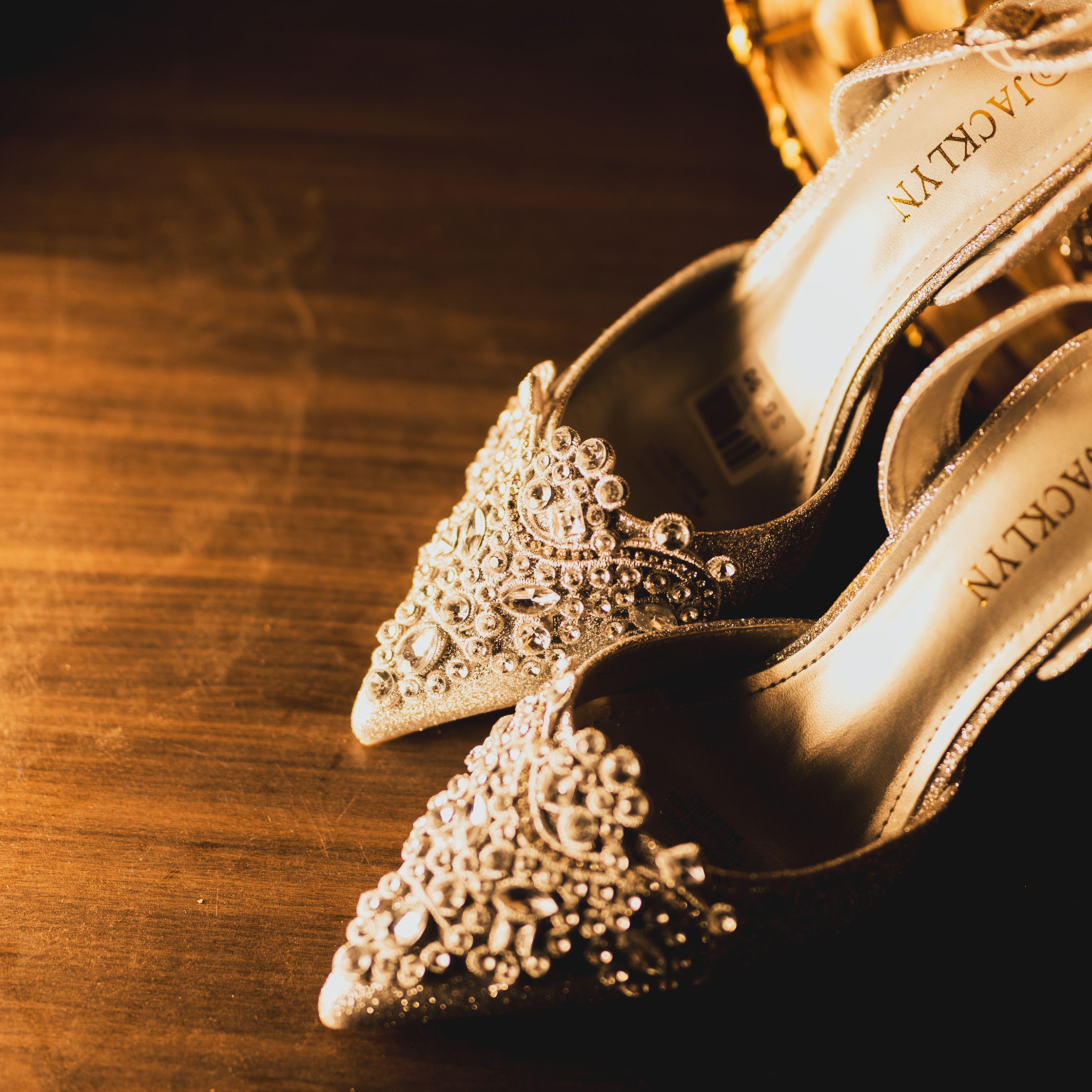 Luxurious high heels adorned with intricate gem patterns on a polished wood surface.