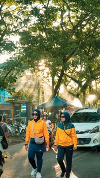 People walking under morning sunlight in Pontianak, Indonesia, creating a vibrant street scene. - Fotografer Sidoarjo