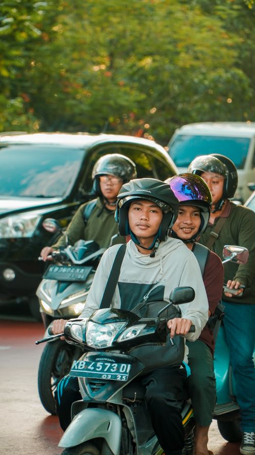Free Teenagers riding motor scooters on an urban street with helmets, showcasing city transportation. Stock Photo