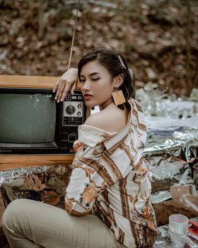 在复古主题的户外照片拍摄中，时尚女性们拿着老式电视合影