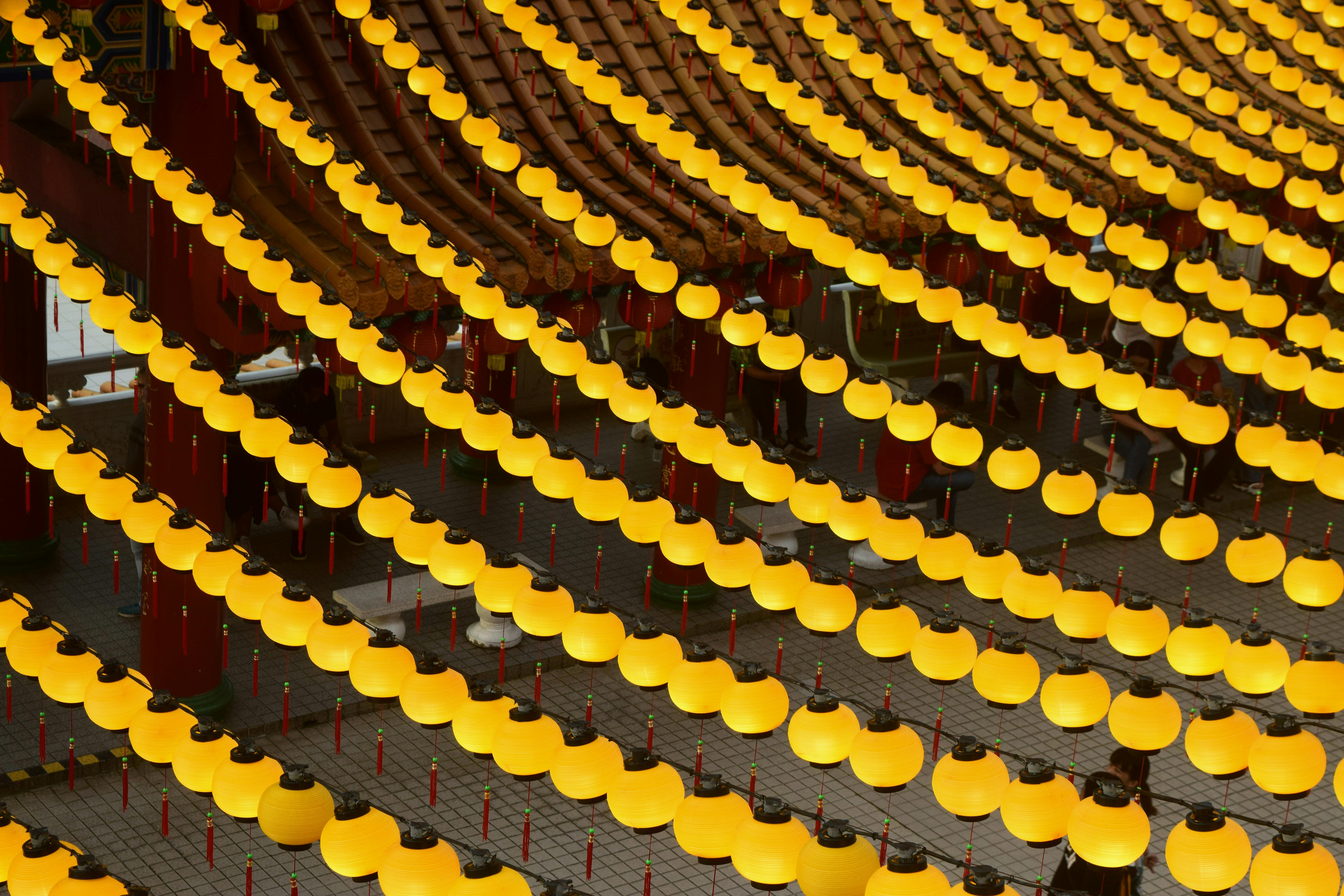 Rows of yellow lanterns illuminating a temple courtyard create a vibrant and festive atmosphere.