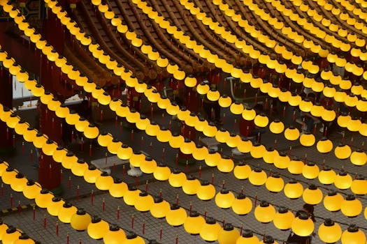 Rows of yellow lanterns illuminating a temple courtyard create a vibrant and festive atmosphere.