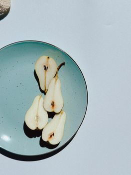 Overhead view of pear halves on a blue ceramic plate, showcasing minimalist food styling.
