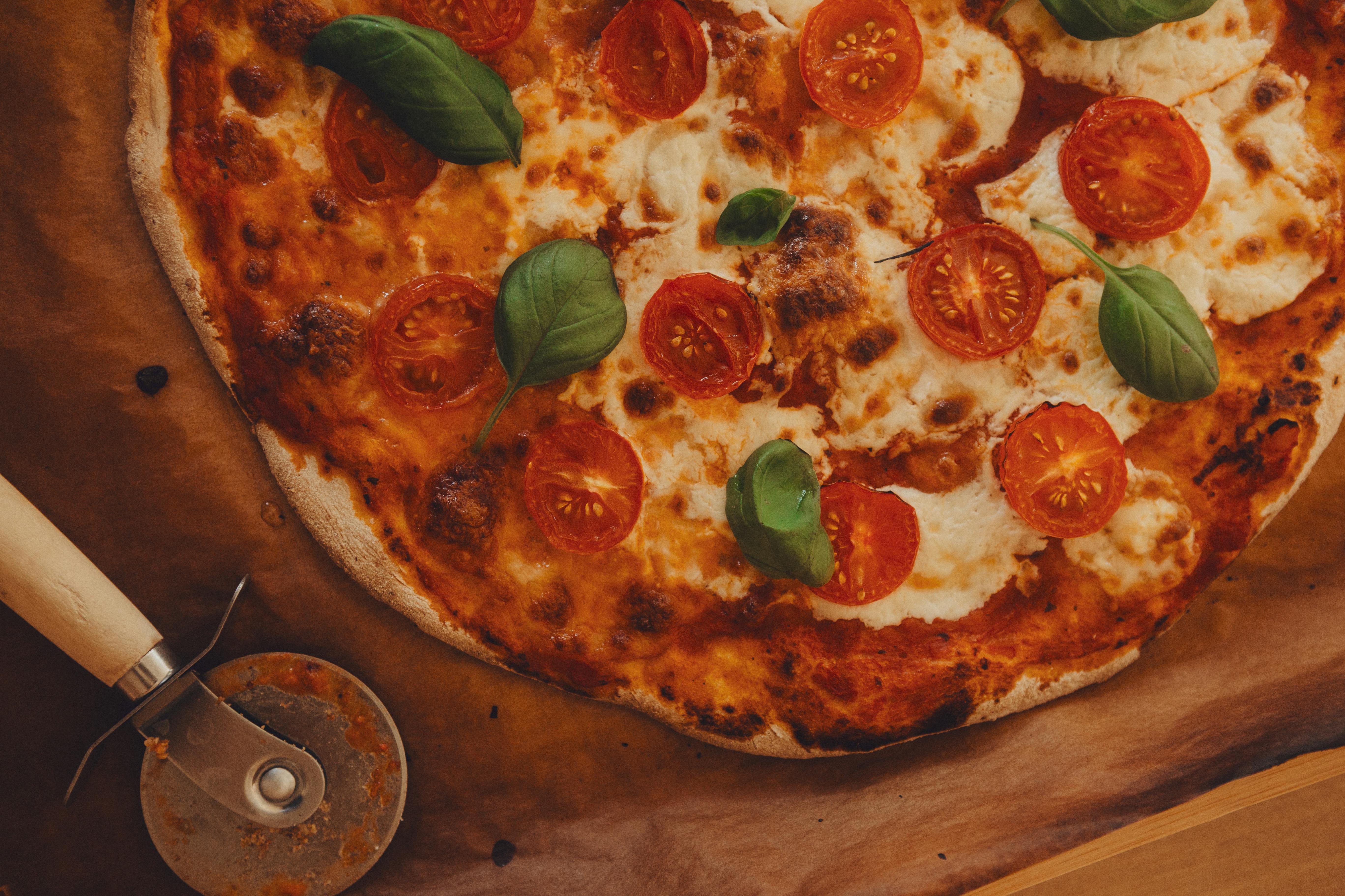 Close-up of a classic Margherita pizza with tomatoes, mozzarella, and basil on a wooden board.