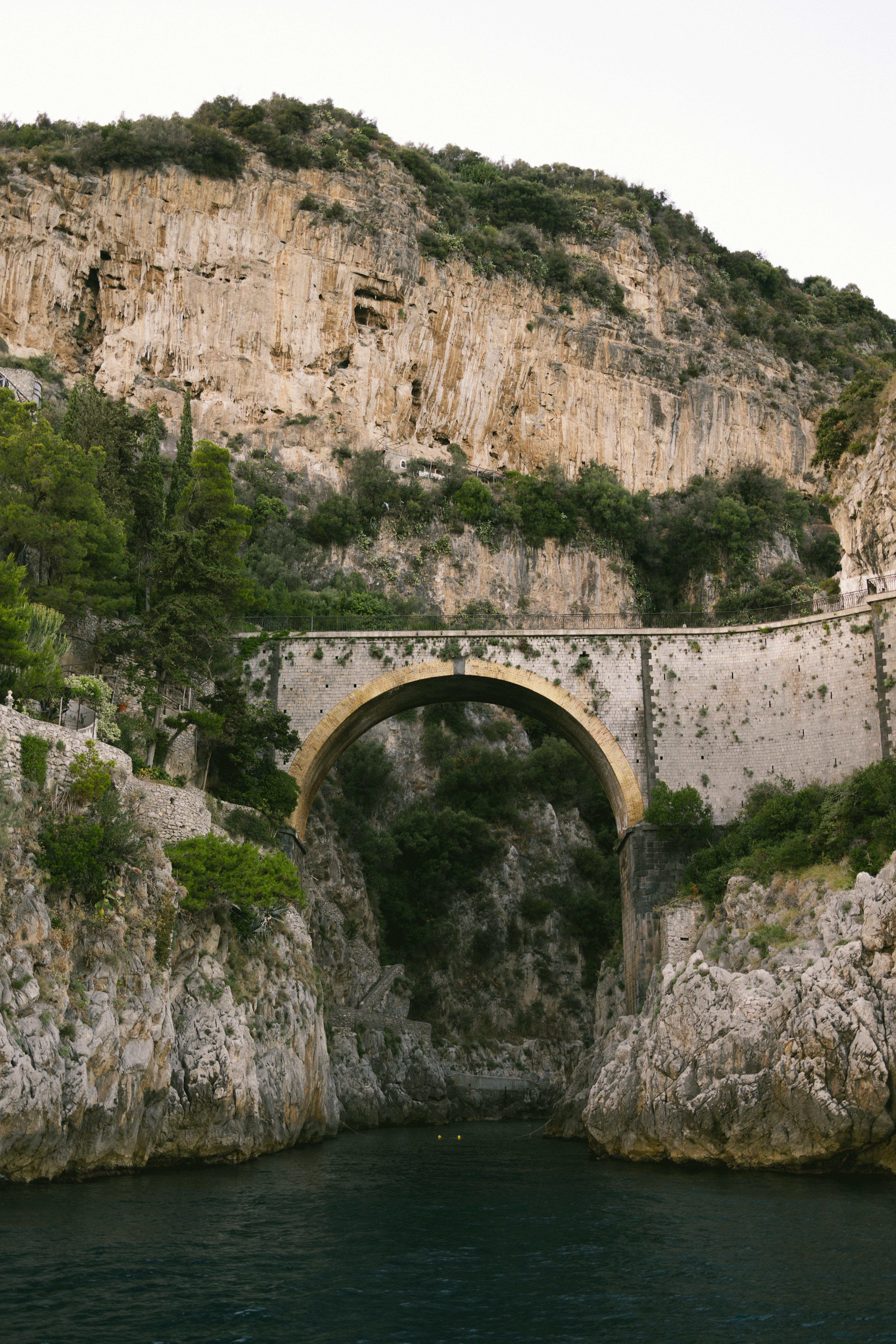 Stunning view of an arch bridge over rocky cliffs in Positano, Italy. Perfect for travel inspiration.