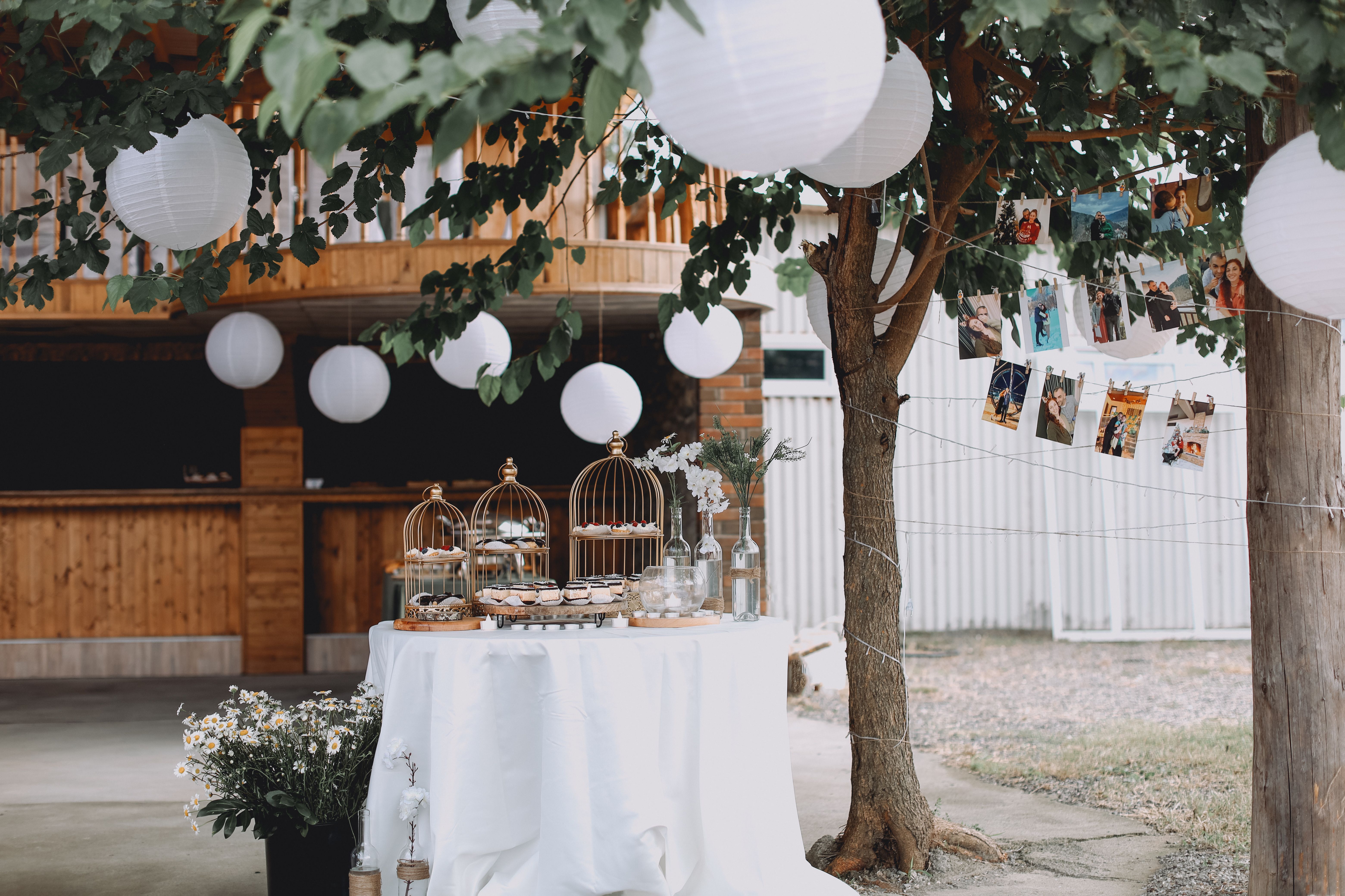 Charming outdoor garden party setup with elegantly decorated dessert table and ambient lighting.