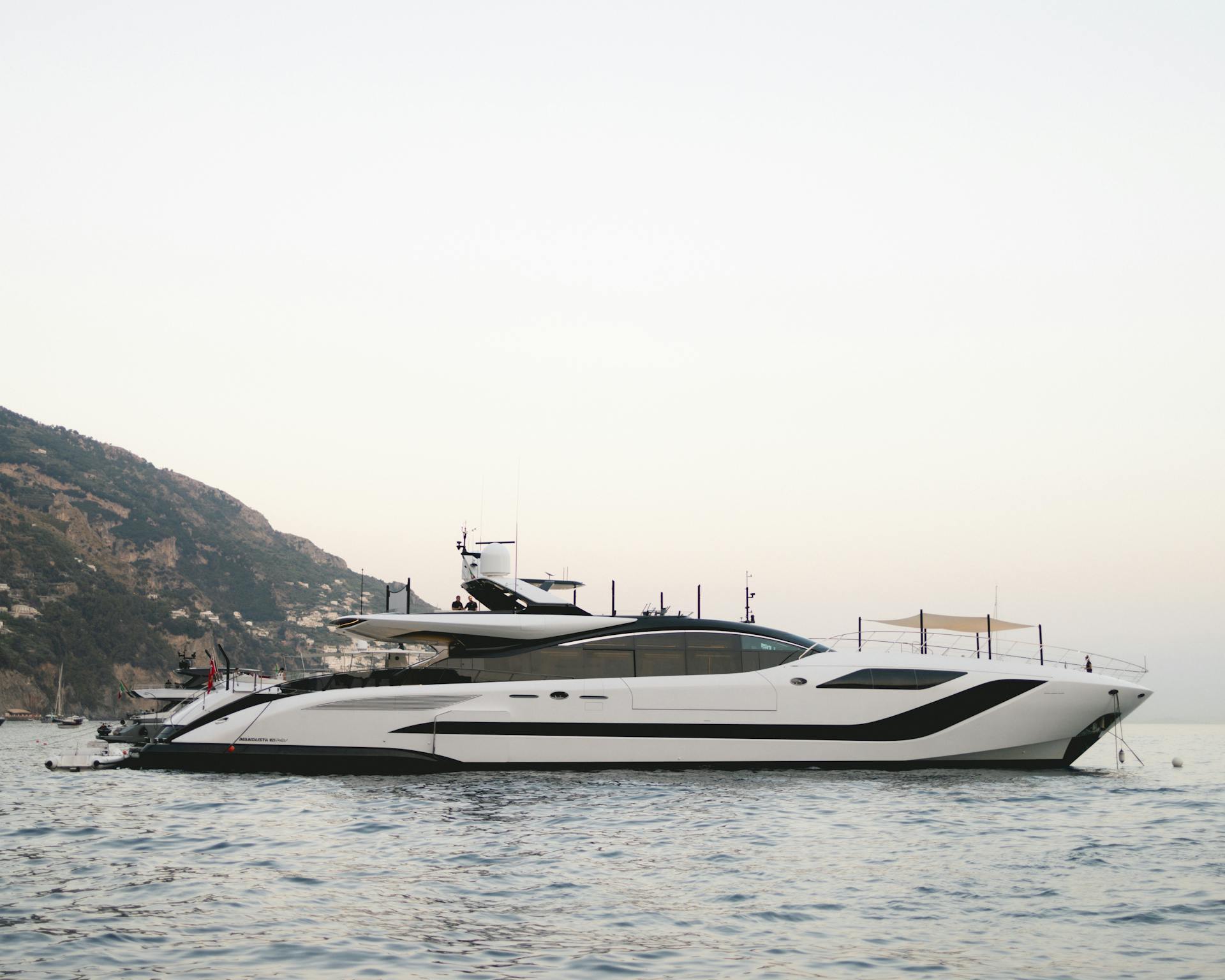 A sleek luxury yacht cruising near the coast of Positano, Italy at sunrise.