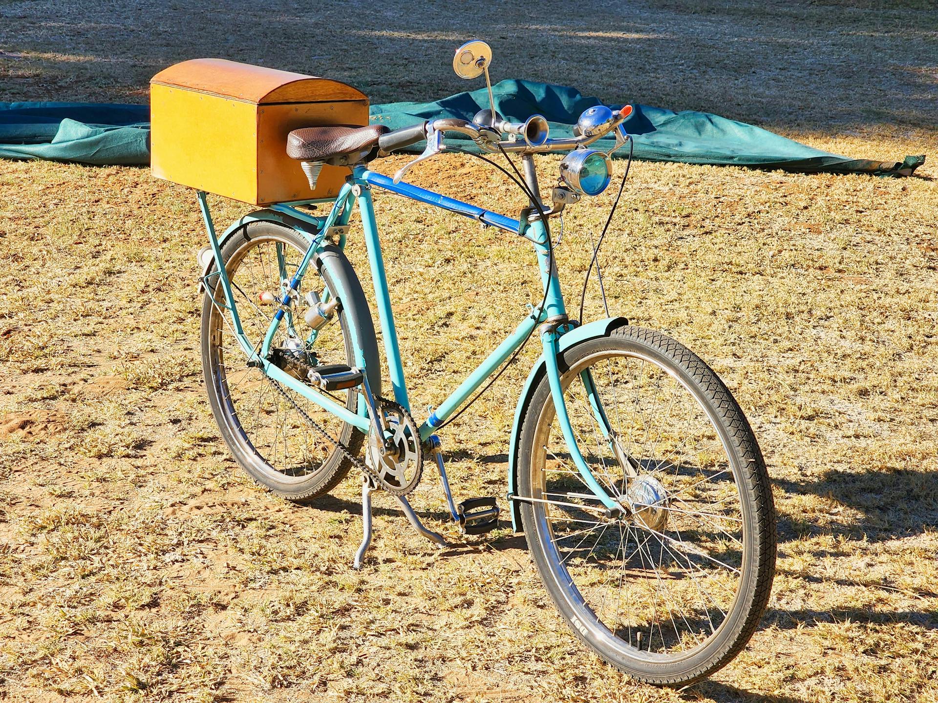 Classic vintage bicycle with a storage box on dry grass in sunny Modimolle, South Africa.