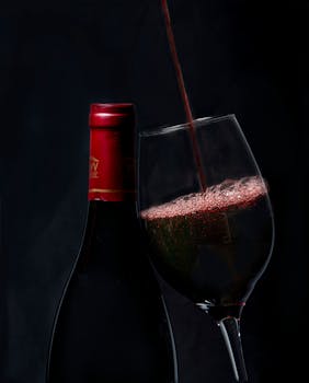 优雅的红酒倒入玻璃杯中，背景是酒瓶，非常适合葡萄酒爱好者