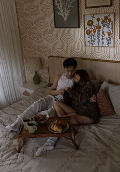 A couple embraces with breakfast in bed, creating a warm and intimate morning setting.