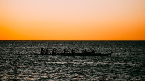 Free Silhouette of canoeists paddling on the sea during a vivid sunset, creating a serene atmosphere. Stock Photo