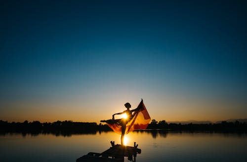 Free Woman Standing in Front of Body of Water Under Clear Blue Sky Stock Photo