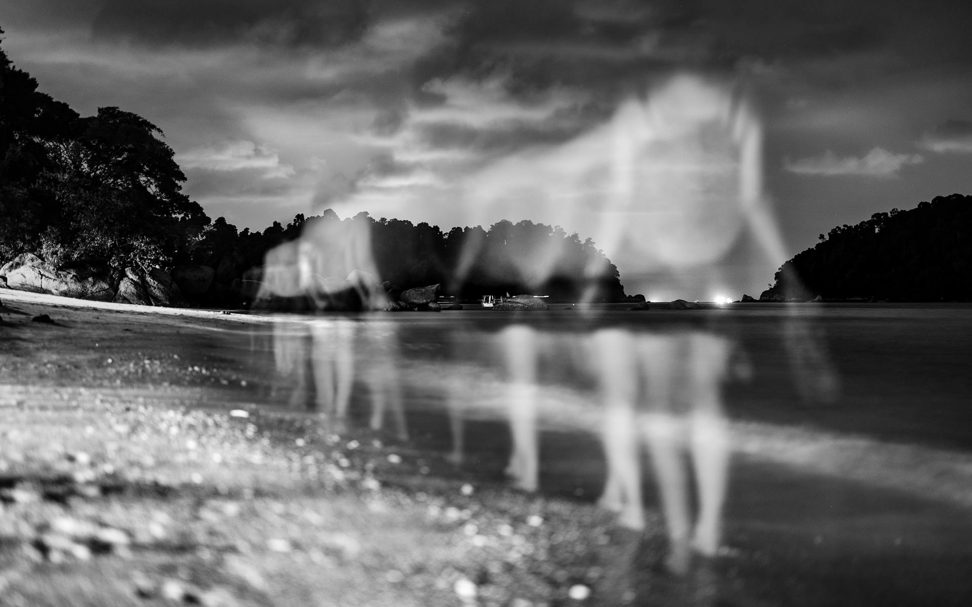 Black and white eerie beach scene with ghostly figures created by multiple exposure