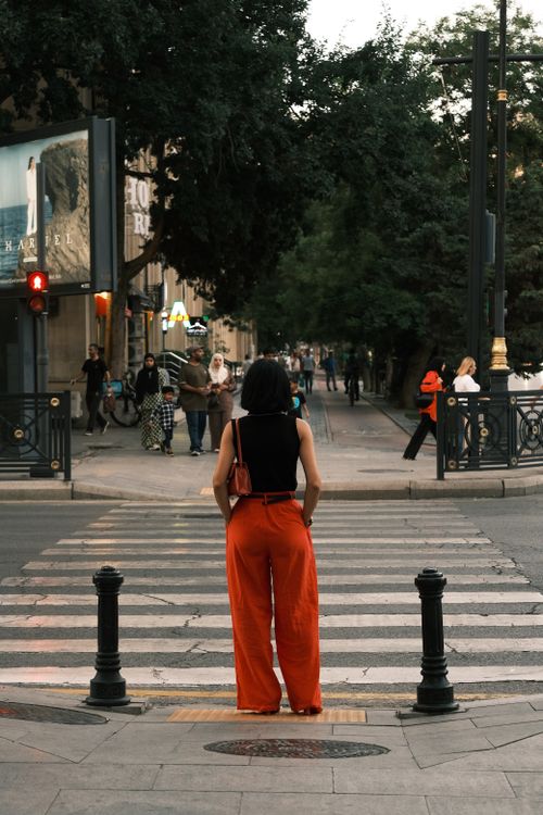 Free Rear view of a woman waiting at a city zebra crossing. Stock Photo