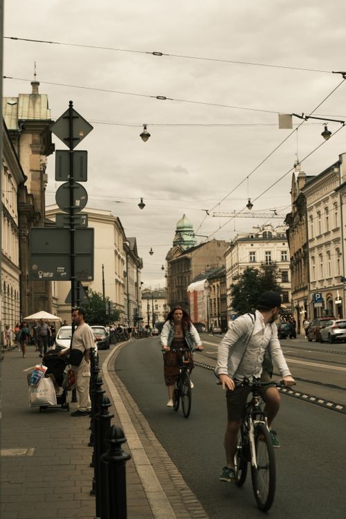 Free Cyclists ride through a bustling city street with historic architecture. Stock Photo