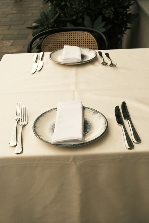 Free Stylish outdoor table setting with elegant cutlery and napkins, perfect for a fine dining experience. Stock Photo