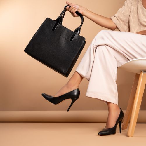 Free Chic fashion studio shoot featuring a woman in stylish black heels and a black leather handbag. Stock Photo