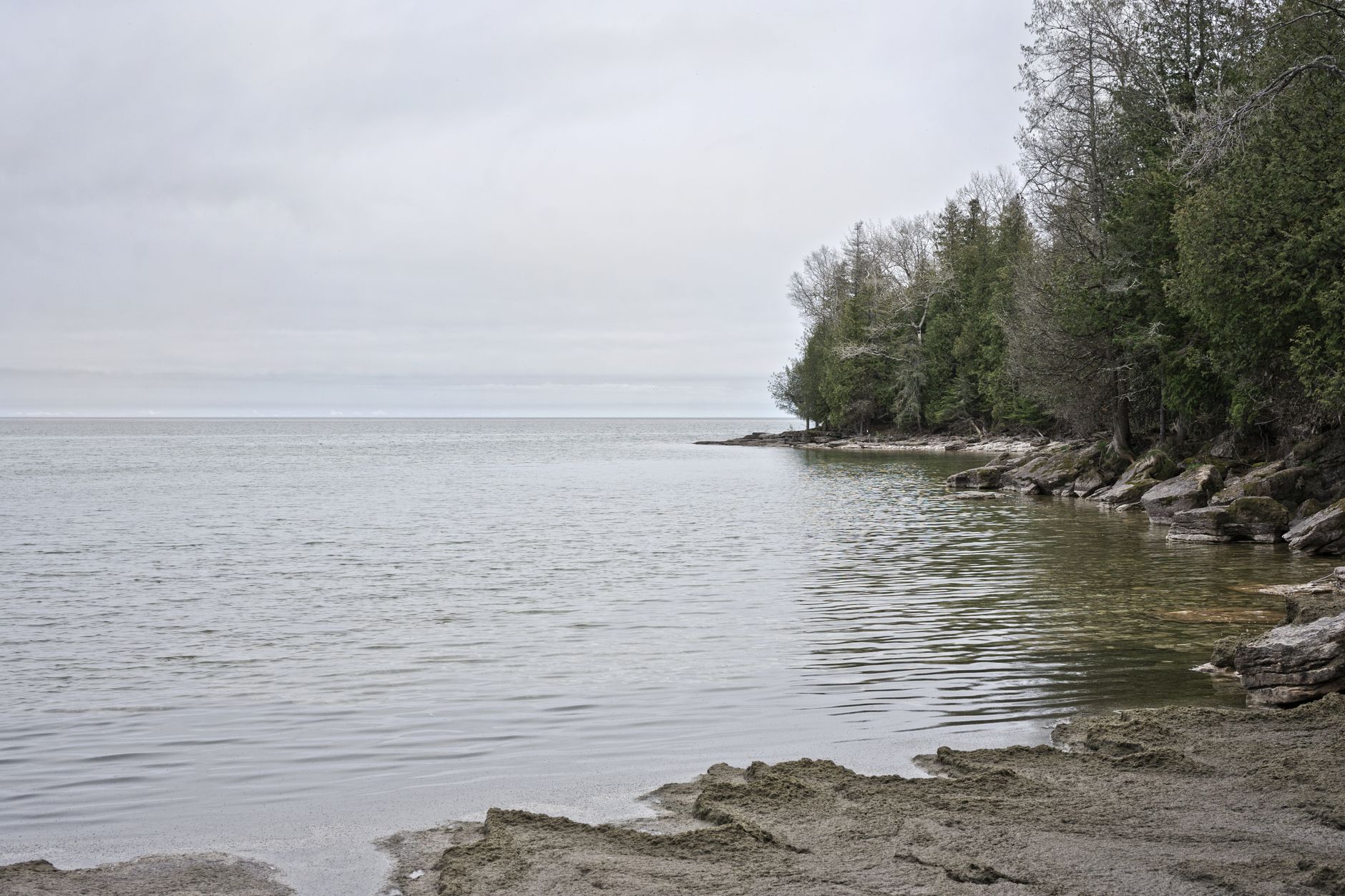 Peaceful view of Lake Michigan's shore in Wisconsin with calm waters and rocky landscape.