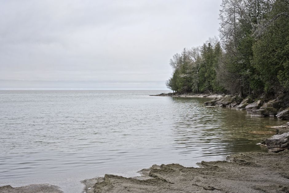 Peaceful view of Lake Michigan's shore in Wisconsin with calm waters and rocky landscape.