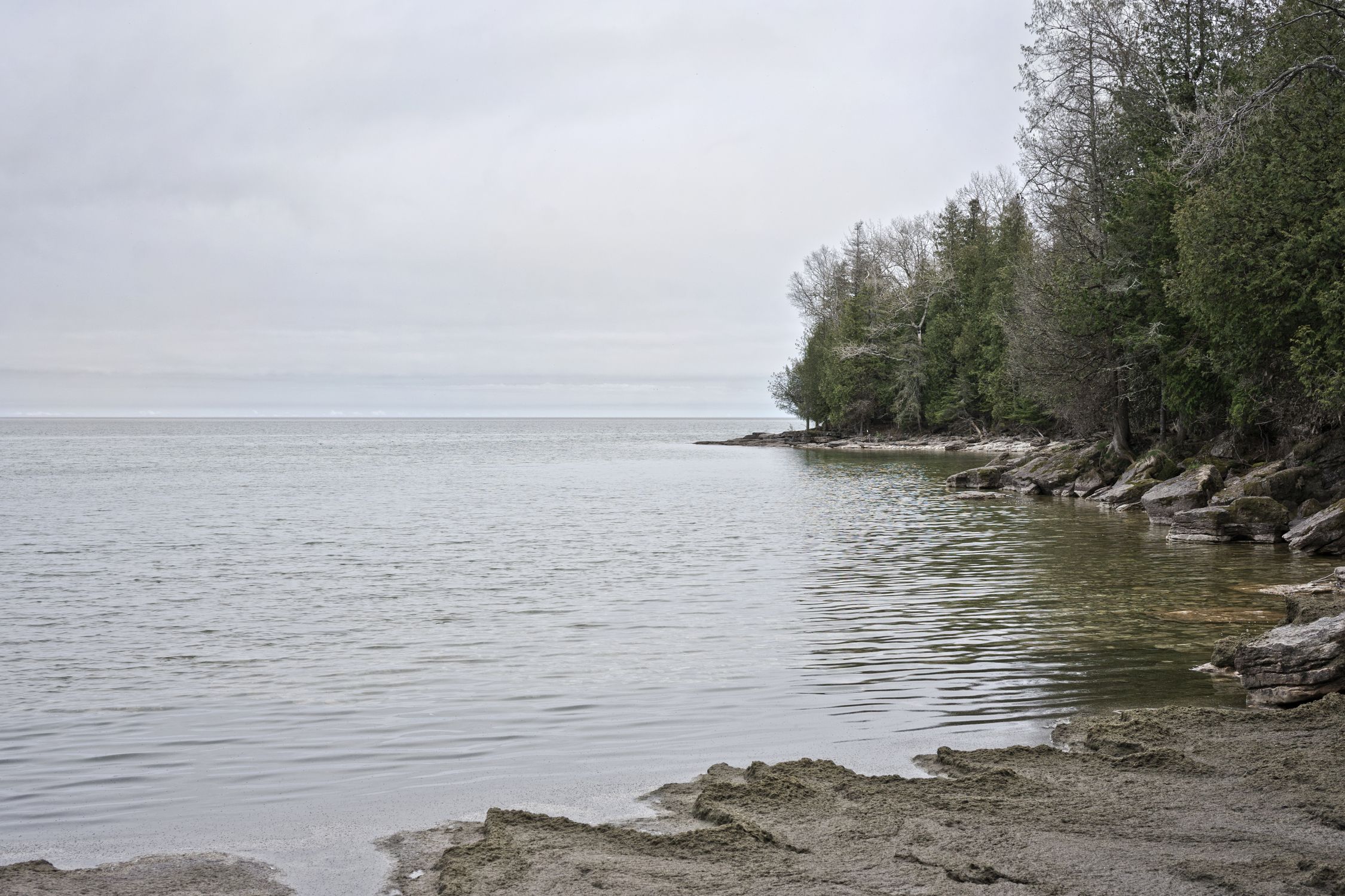 Peaceful view of Lake Michigan's shore in Wisconsin with calm waters and rocky landscape.