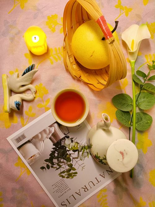 Free A cozy tea setup with fruits, floral decor, and candles on a patterned tablecloth. Stock Photo