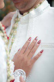 Close-up of a bride's hand on the groom's chest, showcasing elegance and affection.