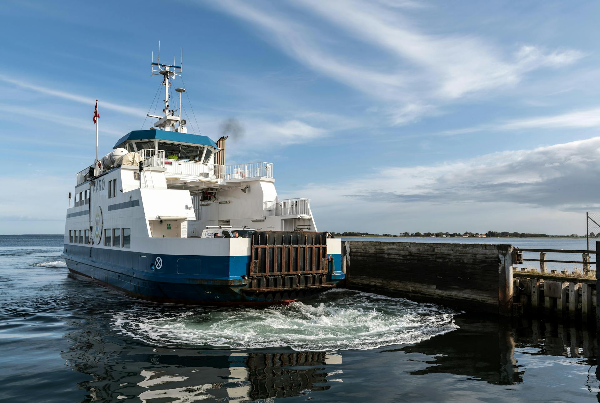 A ferry docked at Årøsund harbor with a clear blue sky, showcasing the serene ocean view.