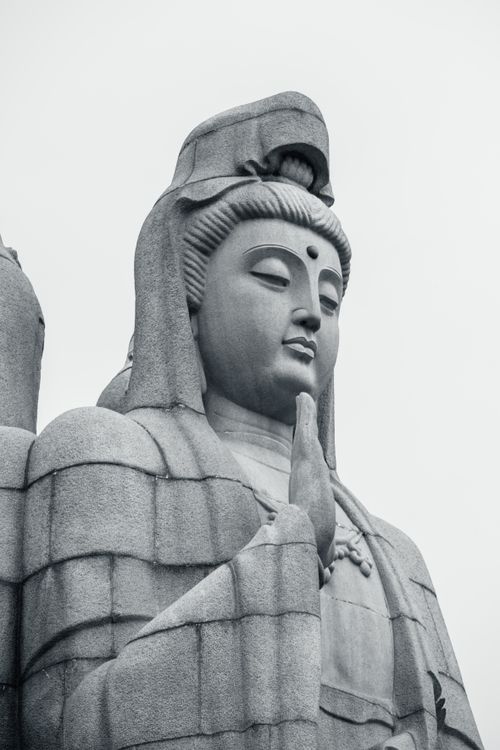 Free A close-up view of a stone Quan Yin statue with serene expression in black and white. Stock Photo