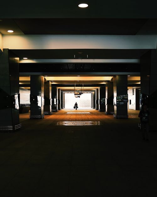 Free Silhouette of a person walking in a symmetrical, underground urban corridor with dramatic lighting. Stock Photo