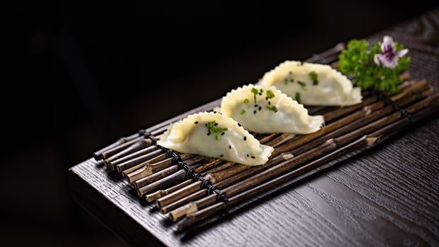 Exquisite dumplings garnished with herbs, served on a bamboo mat, offering a gourmet dining experience.