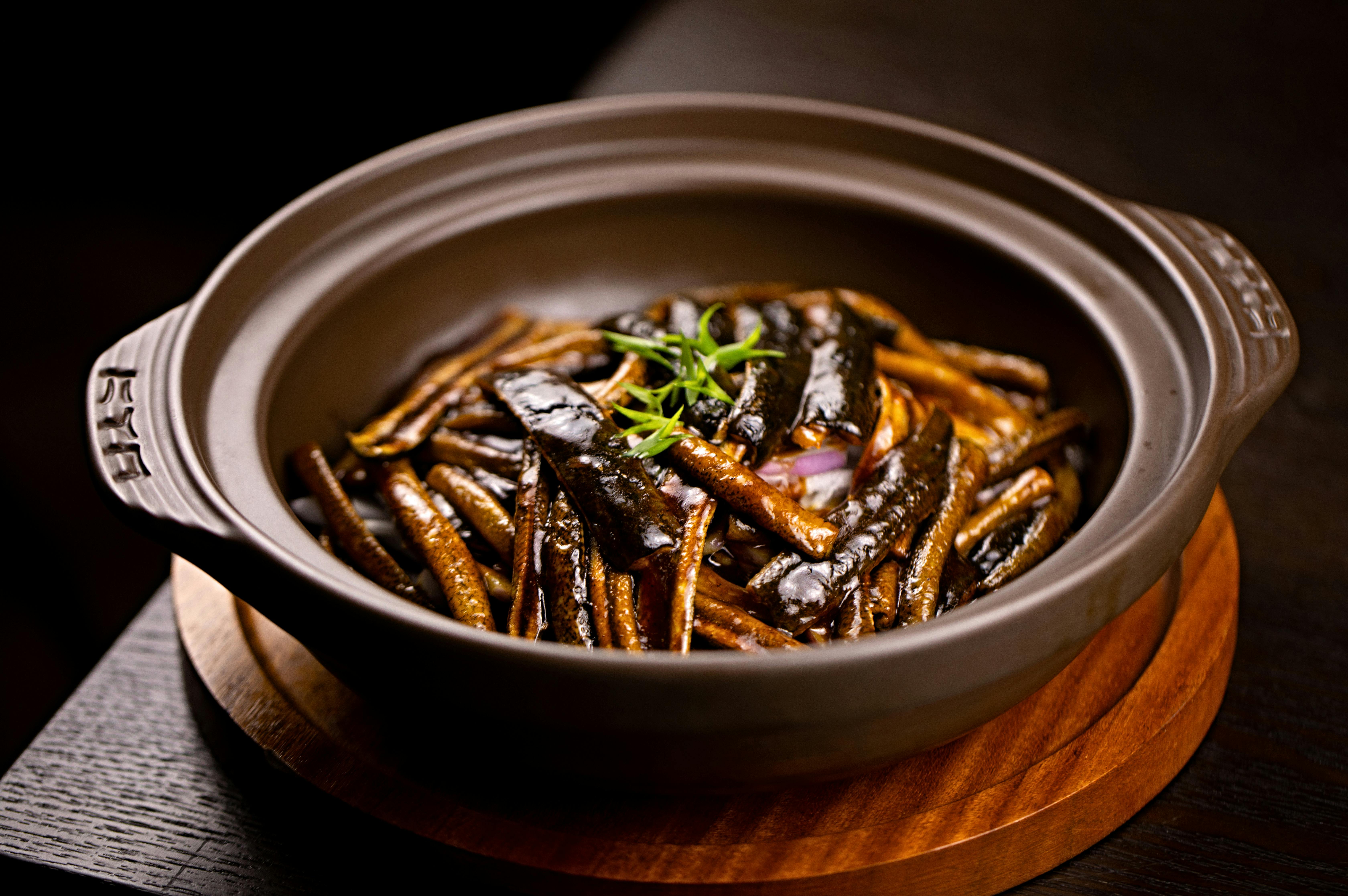 Close-up of a gourmet Asian seafood dish served in a ceramic bowl, captured indoors.