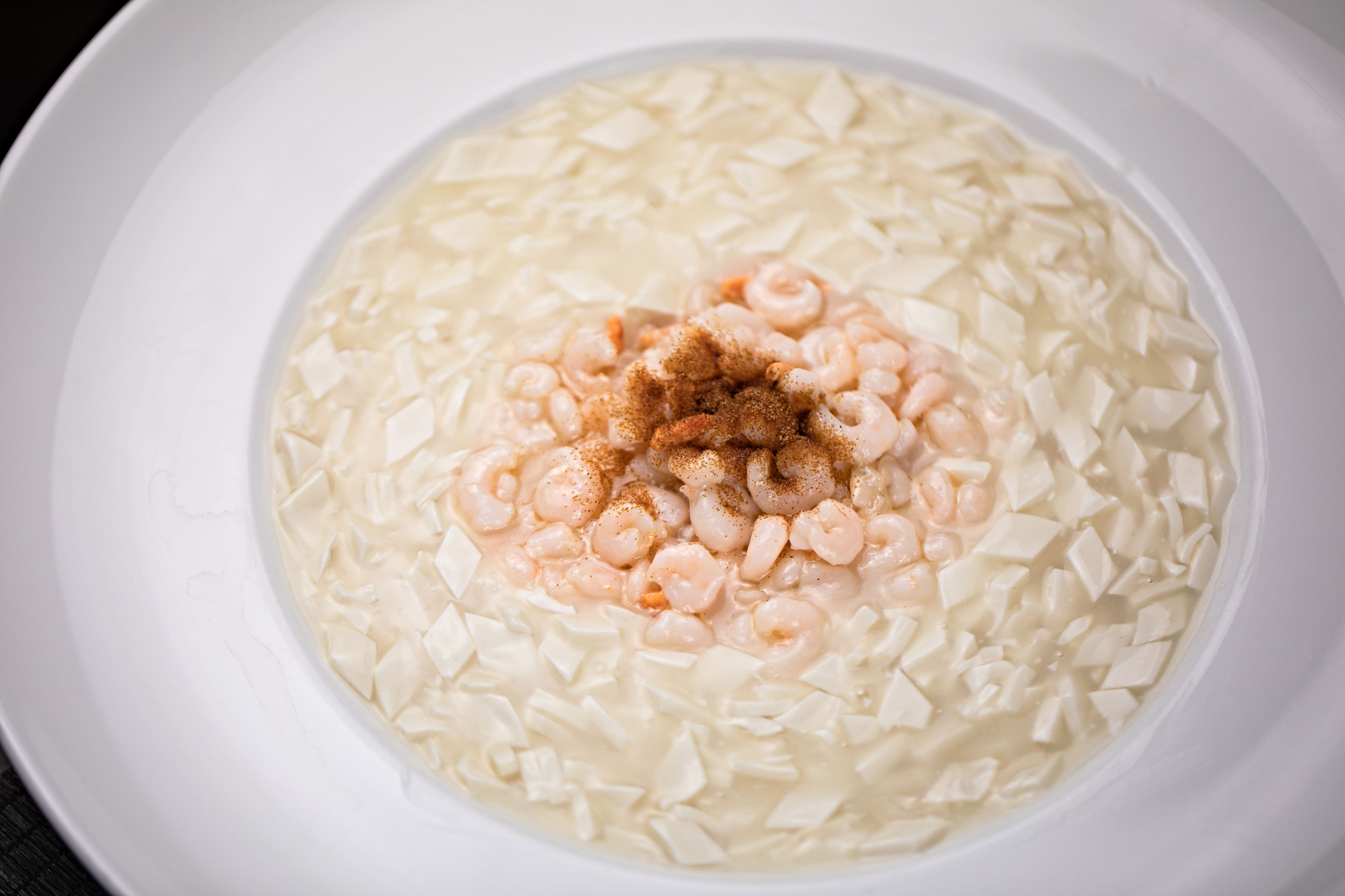 Delicious creamy tofu soup garnished with seasoned shrimp, offering a gourmet meal experience.