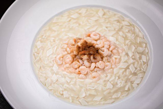 Delicious creamy tofu soup garnished with seasoned shrimp, offering a gourmet meal experience.