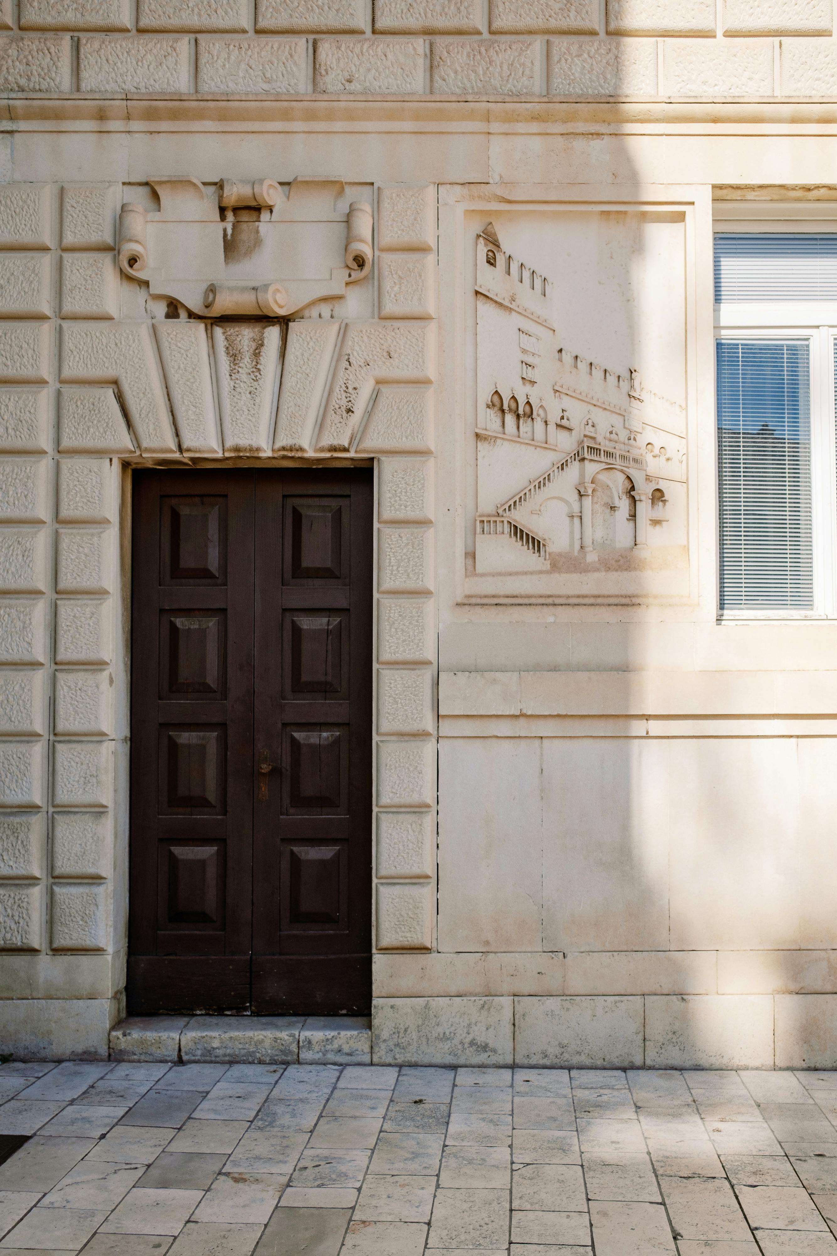 Charming stone facade featuring a dark wooden door and artistic wall engravings.