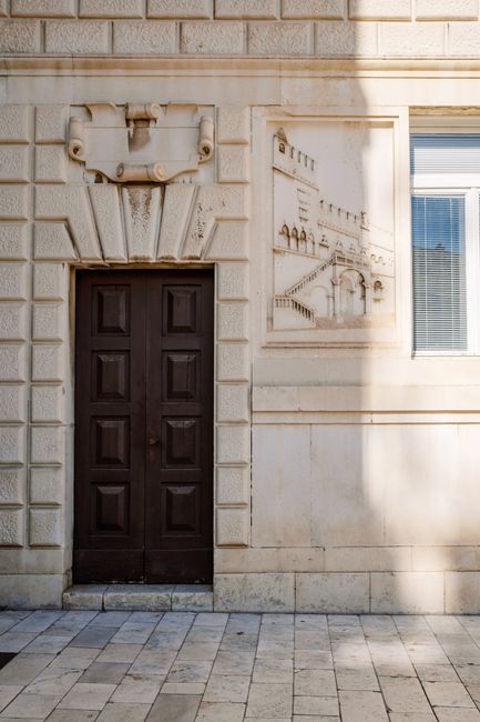 Charming stone facade featuring a dark wooden door and artistic wall engravings.